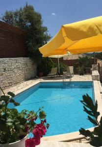 a swimming pool with a yellow umbrella and some flowers at Villa Syvros in Sívros