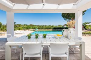 a white table and chairs on a patio with a pool at Villa Syndriani in Paradeísi