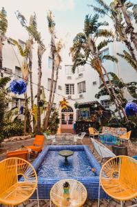 a patio with chairs and a pool and palm trees at Freehand Miami in Miami Beach