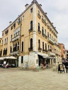 Un gran edificio con mesas y sillas delante. en Ca' Ormesini Lovely Apartment, en Venecia