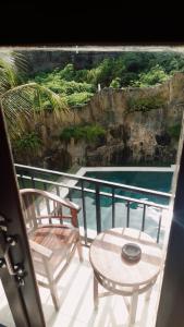 a balcony with a table and chairs and a pool at Devata Giri in Uluwatu