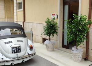 ein weißes Auto, das neben zwei Topfbäumen parkt in der Unterkunft B&B Sweet Home in Grumo Appula