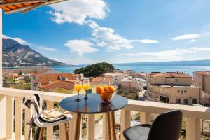 einen Balkon mit einem Tisch und 2 Gläsern Orangensaft in der Unterkunft Golden View Apartment in Duće