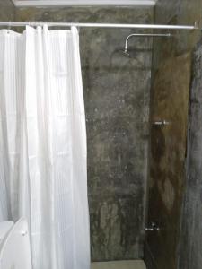 a shower with a white shower curtain in a bathroom at Le Petit Hotel & Restaurant in Negombo