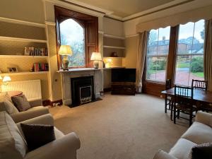 a living room with a fireplace and a table and chairs at Edenwood, The Green, Wetheral in Wetheral