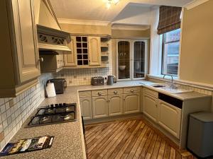 a kitchen with white cabinets and a wooden floor at Edenwood, The Green, Wetheral in Wetheral