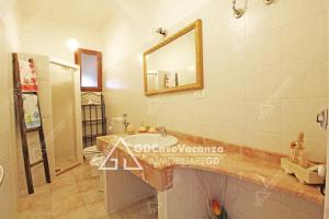 a bathroom with a sink and a toilet and a mirror at GD Case Vacanza - Ville del Rio in Fontanelle