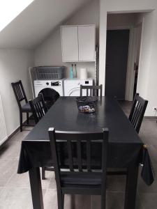 a black dining room table with chairs and a kitchen at Appartement meublé Tilff in Esneux +4 photos