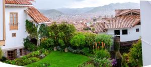 Blick auf eine Stadt mit Häusern und einem grünen Hof in der Unterkunft Eco-Hotel Pension Alemana in Cusco