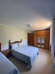 a bedroom with two beds and wooden cabinets at Casa Espetacular no Centro da Serra in Nova Friburgo