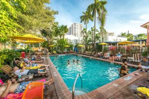un grupo de personas sentadas alrededor de una piscina en un complejo en Freehand Miami en Miami Beach