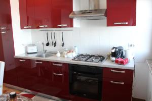 a kitchen with red cabinets and a stove top oven at Villa Sofia in Taormina
