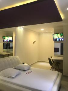 a bedroom with a bed and a desk with two televisions at Motel Monza (Adult Only) in Santos