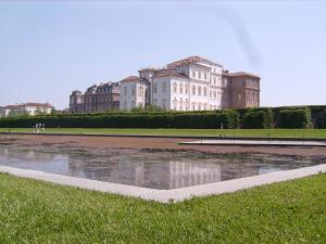 un grande edificio di fronte a un laghetto in un parco di Monolocale Dormire alla Reggia a Venaria Reale