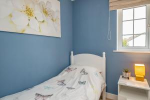 a bedroom with blue walls and a bed and a window at Shrimper's Cottage in Wadebridge