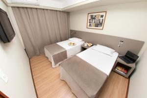 a hotel room with two beds and a tv at Alta Reggia Plaza Hotel in Curitiba