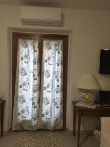 um quarto com duas cortinas e uma mesa com um candeeiro em Casa Azzurra em Santa Teresa Gallura