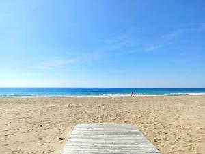 a wooden pier on the beach with a person in the ocean at Casa al mare Le Dune in Lido Marini