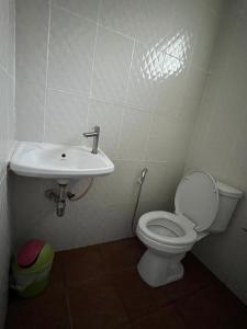 a bathroom with a toilet and a sink at กรีนเกสท์เฮ้าส์ พนัสนิคม in Phanat Nikhom