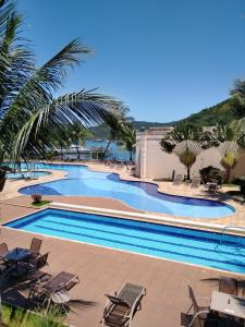 a large swimming pool with chairs and palm trees at PORTO MARINA MONT BLANC RESORT in Mangaratiba