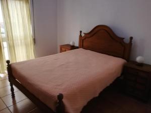 a bedroom with a large bed with a wooden headboard at Apartamento Tiago in Sines