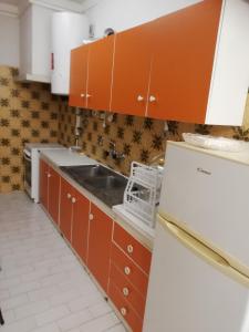 cocina con armarios de color naranja y fregadero en Apartamento Tiago, en Sines