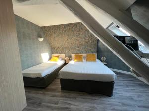 two beds in a room with an attic at Contact Hotel Hôtel De Troyes in Troyes
