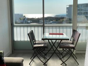 a glass table and two chairs on a balcony at Studio front de mer 'Le Soleillan' in La Grande Motte +11 photos