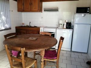 uma cozinha com uma mesa de madeira e um frigorífico branco em Villa Lélou em Les Mignots