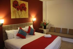 a bedroom with a large bed with red and green pillows at Hotel Arenas del Pacifico in Santa Cruz Huatulco