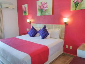 - une chambre avec un lit aux murs rouge et violet dans l'établissement Hotel Arenas del Pacifico, à Santa Cruz Huatulco