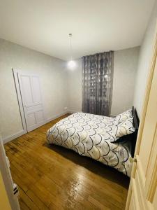 1 dormitorio con 1 cama y suelo de madera en Appartement proche de la ville et du parc du Truchet en Saint-Claude