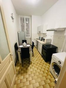 una pequeña cocina con mesa, sillas y lavadora en Appartement proche de la ville et du parc du Truchet, en Saint-Claude
