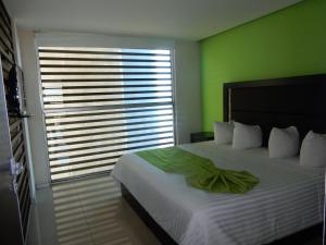 1 dormitorio con 1 cama grande y pared verde en Hotel Torres Eugenia, en Coatzacoalcos