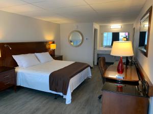 a hotel room with a bed and a desk with a lamp at The Branson Welcome Inn in Branson