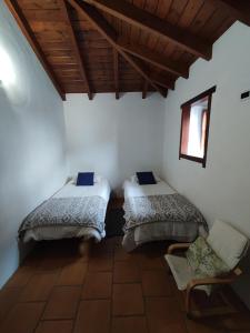 Habitación con 2 camas y una silla. en La Fortaleza, en Erjos-El Tanque