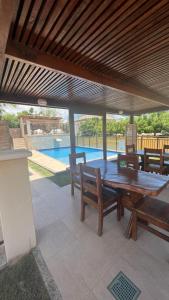 a patio with a wooden table and benches and a pool at Sol e Mar - AP 05 - Be Summer in Flecheiras