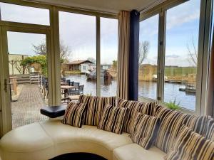 Pura Vida del Rio في Oud-Ade: أريكة في غرفة معيشة مطلة على الماء