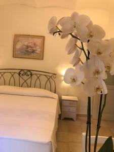 un jarrón lleno de flores blancas en un dormitorio en Domo Antiga Guest Rooms, en Sorso
