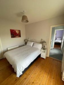 a bedroom with a large white bed and wooden floors at Drumville House Self Catering in Castlemaine