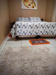 a bedroom with a bed and two rugs on the floor at Recanto Santa Teresa in Guarapuava