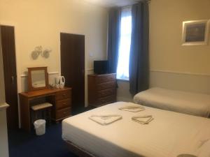 a room with two beds and a desk and a mirror at Canasta Hotel in Blackpool