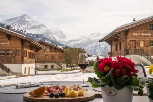 a table with a plate of food and a glass of wine at Chalet Spitzhorn - Your Peak Getaway - Private Terrasse & gratis Parkplatz in Gsteig