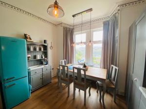Upper Villa, Tighnabruiach, Argyll & Bute في تينابرويك: مطبخ مع طاولة خشبية وثلاجة زرقاء