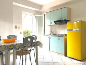 a kitchen with a table with chairs and a yellow refrigerator at Villaggio Calipso in Calopezzati