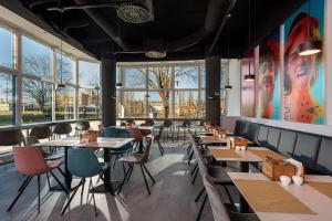 un restaurante con mesas, sillas y ventanas en ibis Styles Berlin Treptow en Berlín