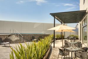 a patio with tables and chairs and an umbrella at Fiesta Inn Guadalajara Aeropuerto in Guadalajara