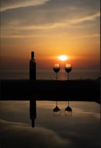 a sunset with two wine glasses and a bottle at The Lighthouse Sunset View Suites in Akrotiri