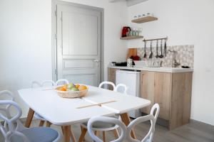 a white kitchen with a white table and chairs at The Lighthouse Sunset View Suites in Akrotiri