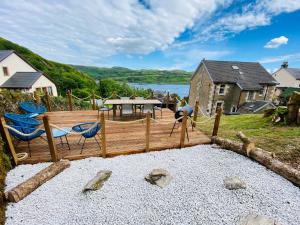 um deque de madeira com cadeiras e uma mesa com vista para a água em Upper Villa, Tighnabruiach, Argyll & Bute em Tighnabruaich